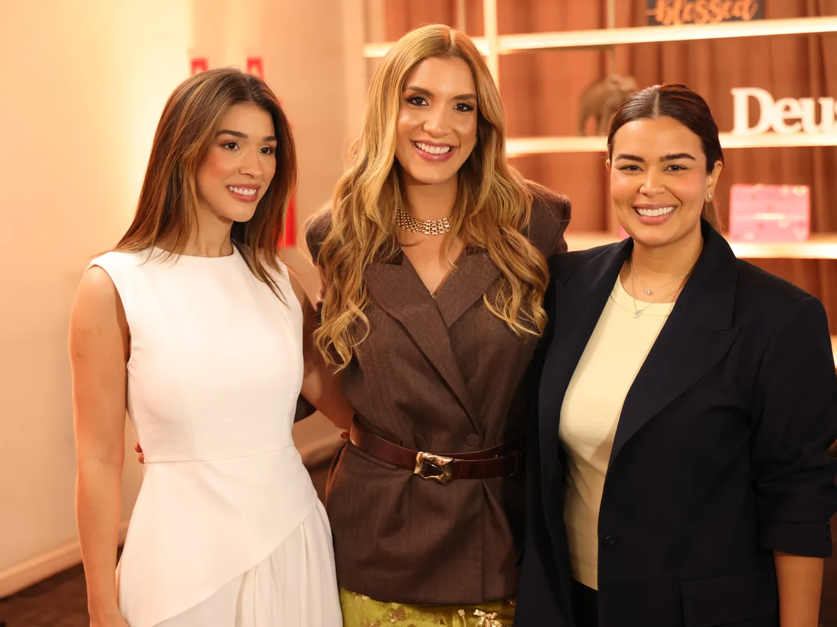 Três participantes posando juntas no espaço de ativação